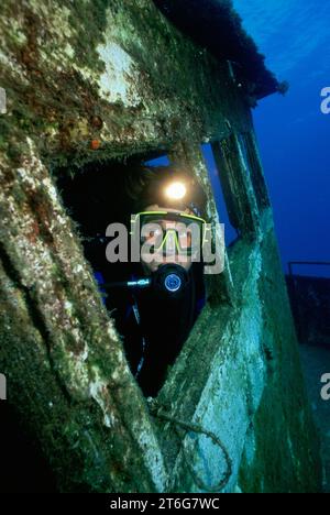 Plongeur masculin avec lampe frontale sur épave, Bahamas Banque D'Images