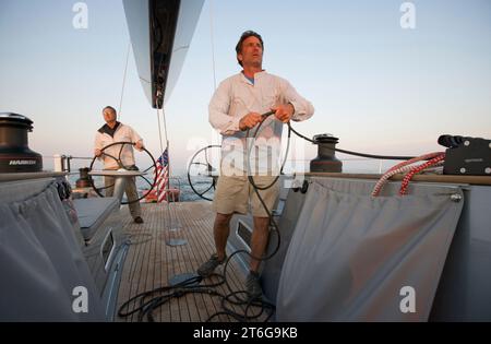 L'équipage navigue sur un yacht de course à la maison au crépuscule Banque D'Images