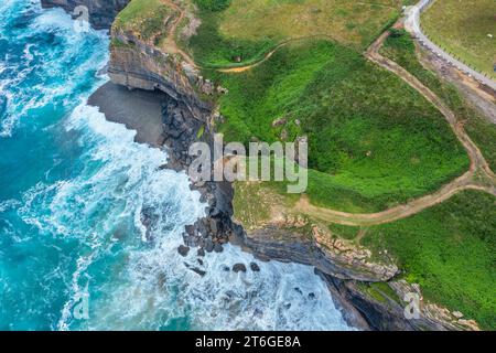 Vue aérienne d'un paysage côtier avec falaises rocheuses et prairies verdoyantes. Cantabrie, Espagne. Banque D'Images