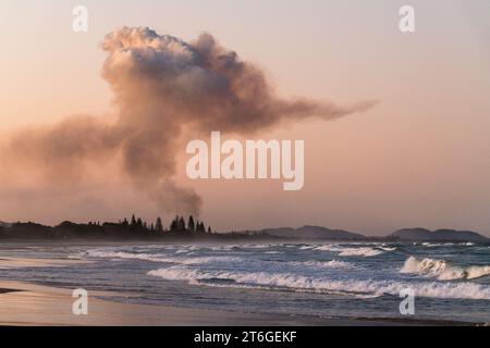 Paysage côtier de coucher de soleil avec champ de canne à sucre brûlant de la fumée à Brunswick Heads, près de Byron Bay, Nouvelle-Galles du Sud - Une fusion unique de beauté naturelle a Banque D'Images