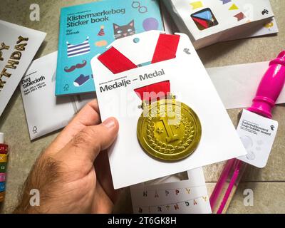 Paris, France - 3 octobre 2023 : une main masculine saisit une médaille d'or portant le numéro un inscrit, achetée au magasin Tiger, exposée en évidence Banque D'Images