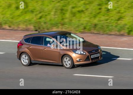 2014 Ford Focus Titanium Navigator Turbo T EcoBoost 125 Start/Stop Brown car Hatchback essence 998 cc, 1,0 moteurs EcoBoost éconétiques turbocompressés ; se déplaçant à grande vitesse sur l'autoroute M6 dans le Grand Manchester, Royaume-Uni Banque D'Images