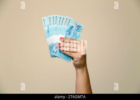 Plusieurs centaines de billets réels - de l'argent du Brésil dans une main de femme avec des ongles rouges - dos de note Banque D'Images