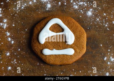 Un biscuit sucré, recouvert de glaçage blanc en forme de lettre A, repose sur une vieille planche entourée de farine Banque D'Images