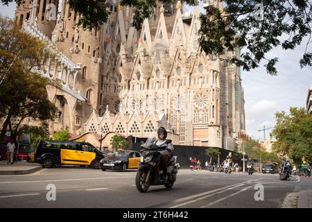 Scooter dans les rues de Barcelone, avec des taxis et la Sagrada Familia, de l'architecte Gaudi, en arrière-plan Banque D'Images