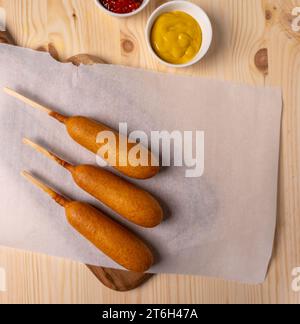 Vue aérienne, à plat de chiens de maïs frits sur papier parchemin avec ketchup et moutarde. Banque D'Images