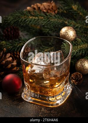 Verre de whisky et de glace sur surface en bois avec décorations de Noël en arrière-plan Banque D'Images