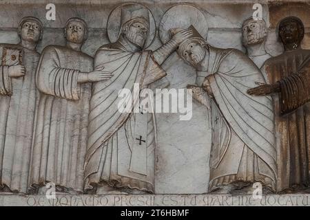 Scène de «Storie di San Martino», une série de reliefs romanesque13e siècle sur la façade du Duomo di San Martino, Lucques, Toscane, Italie. Les reliefs, représentant des scènes de la vie de Saint Martin de Tours, peuvent être l'œuvre du maître sculpteur lombard Guido ou Guidetto di Bonagiunta Bigarelli, connu sous le nom de Guido da Como (1220 - c. 1257). Banque D'Images