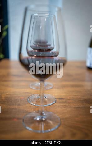 Verres de vin rouge, sur la table en bois kaki marron. Motif et texture. Ligne. Concept Infinity. Présentation. Boisson alcoolisée. In vino veritas. Banque D'Images