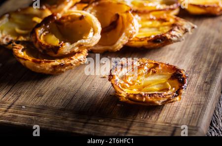 Mini-tartes faites de pâte feuilletée et de pommes tranchées sur une planche à découper. Gâteaux aux pommes France - gros plan. Banque D'Images