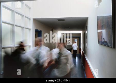 Un mouvement image floue d'un groupe d'élèves marchant dans le couloir d'une école secondaire complète, Angleterre, Royaume-Uni Banque D'Images