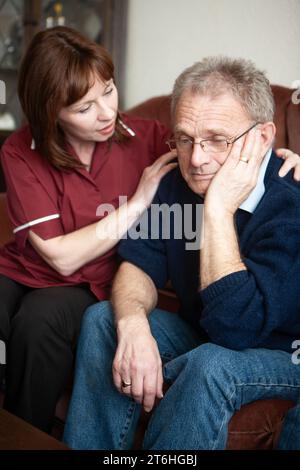 Aider les personnes âgées : le conseil en deuil. Un professionnel de la santé en visite prenant un moment pour consoler un homme âgé. À partir d'une série d'images associées. Banque D'Images
