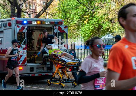 Les EMT chargent un coureur dans leur ambulance alors que les coureurs traversent Harlem à New York près de la marque des 22 miles près du parc Mount Morris lors de la course du marathon de New York du TCS le dimanche 5 novembre 2023. (© Richard B. Levine) Banque D'Images