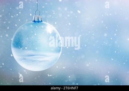 Boule de verre transparent sur fond d'hiver flou avec des flocons de neige Banque D'Images