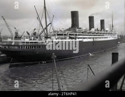 Années 1930, historique, un grand paquebot à vapeur à trois entonnoirs amarré à un quai, Angleterre, Royaume-Uni, le RMS Berengaria (ancien SS Imperator) à Southampton. Construit à l'origine sur les chantiers navals Vulcan à Hambourg, en Allemagne, et transportant 83 canots de sauvetage, capables de contenir 5 500 personnes, lorsque la construction a pris fin sur lui en 1913, il était le plus grand navire à passagers du monde. Banque D'Images