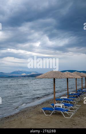 Kalamaki, Corfou, Grèce, chaises longues et parasols à la plage de Kalamaki dans le nord-est de l'île grecque de Corfou, en arrière-plan le continent de l'Albanie Banque D'Images