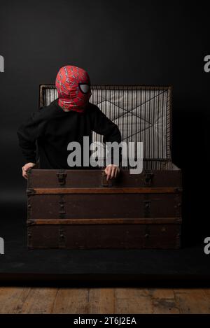 Garçon habillé comme Spiderman sort de la poitrine en bois Banque D'Images