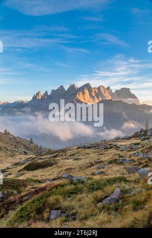 Italie, Vénétie, quartier de Belluno, Falcade, coucher de soleil d'automne avec un faible brouillard sur la vallée et vue sur le côté nord de la Pale di San Martino du mont Pradazzo, Dolomites Banque D'Images