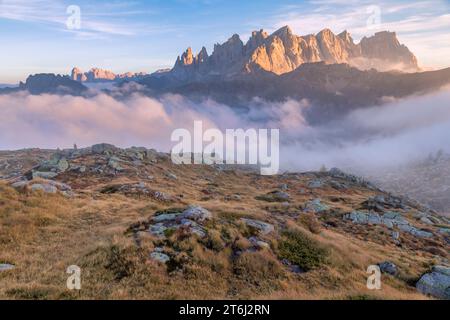 Italie, Vénétie, quartier de Belluno, Falcade, coucher de soleil d'automne avec un faible brouillard sur la vallée et vue sur le côté nord de la Pale di San Martino du mont Pradazzo, Dolomites Banque D'Images