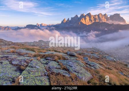 Italie, Vénétie, quartier de Belluno, Falcade, coucher de soleil d'automne avec un faible brouillard sur la vallée et vue sur le côté nord de la Pale di San Martino du mont Pradazzo, Dolomites Banque D'Images