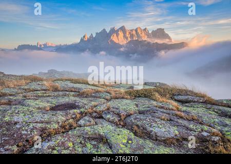 Italie, Vénétie, quartier de Belluno, Falcade, coucher de soleil d'automne avec un faible brouillard sur la vallée et vue sur le côté nord de la Pale di San Martino du mont Pradazzo, Dolomites Banque D'Images