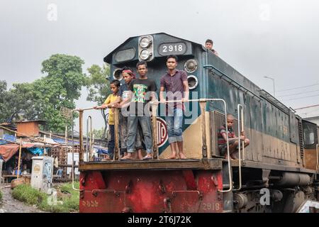 Enfants dans la locomotive d'un train traversant la colonie de Tejgaon construit le long de voies ferrées, dans le bidonville de Tejgaon, Dhaka (Bangladesh) Banque D'Images