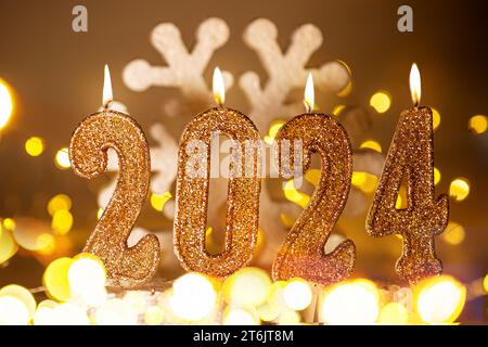 Année 2024 bougies dorées. Affiche de bonne année 2024. Fond de Noël avec des numéros d'or 2024 sur le fond d'un flocon de neige Banque D'Images