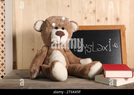 Ours en peluche, petit tableau noir avec le mot Dyslexia et des livres sur la table en bois Banque D'Images