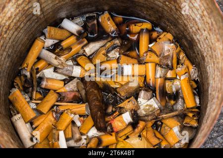 Mégots de cigarettes mouillés jetés dans un cendrier en métal. Banque D'Images