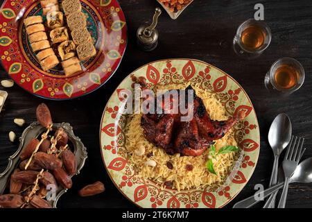 Top View riz Biryani avec poulet épicé rôti, servi avec du Bklava et des dattes fruits pour la fête musulmane Banque D'Images