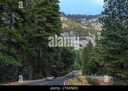 Une voiture conduisant sur une paisible route vide dans le parc national de Yosemite, en Californie Banque D'Images