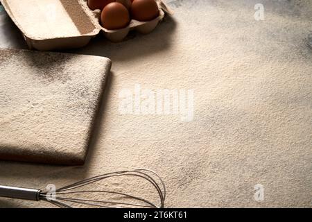 Fond de cuisson avec de la farine, planche à découper, œufs sur une table, vue photo à angle élevé. Banque D'Images