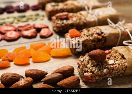 Différentes barres de granola savoureuses et des ingrédients sur la table en bois, closeup Banque D'Images