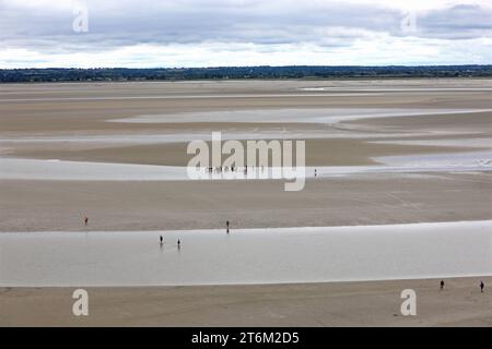 Vue panoramique depuis l'abbaye du Mont Saint Michel en Normandie dans le nord de la France et les petits gens marchant sur le sable Banque D'Images