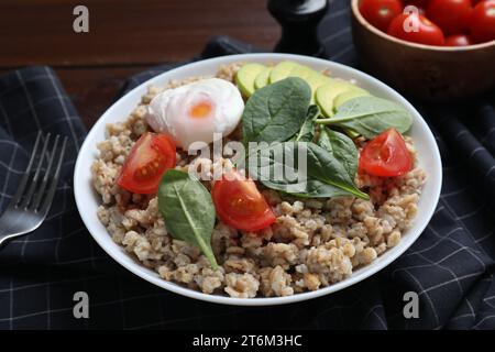 Délicieux flocons d'avoine bouillis avec œuf poché, tomate, avocat et fourchette sur la table, gros plan Banque D'Images