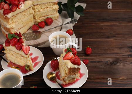 Gâteau savoureux avec fraises fraîches, menthe et tasses de café sur la table en bois. Espace pour le texte Banque D'Images