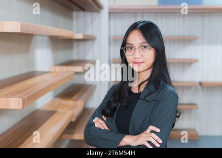 Femme d'affaires asiatique ou freelance debout près du bureau dans le bureau habillé dans des vêtements formels Banque D'Images