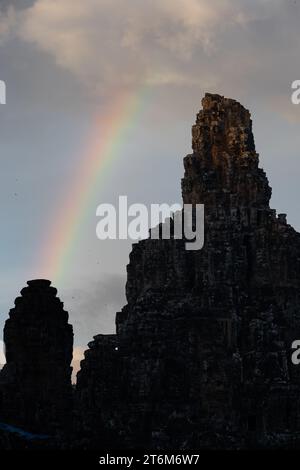 Temple Bayon, Siem Reap, Cambodge dans la lumière de fin de soirée. Un arc-en-ciel est visible dans le ciel. Banque D'Images