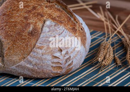 pain artisanal de fermentation naturelle prêt sur table à côté des branches de blé. Banque D'Images