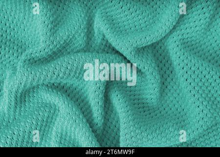 Texture de tissu de laine à tricoter froissée et froissée de couleur turquoise. Fond de tissu tricoté avec motif de points. Structure textile, surface en tissu, weav Banque D'Images