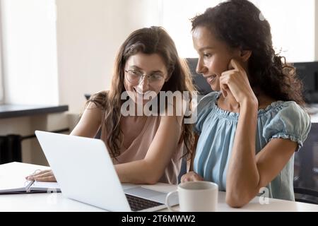 Deux collègues de bureau heureux engagés utilisant l'ordinateur portable ensemble Banque D'Images
