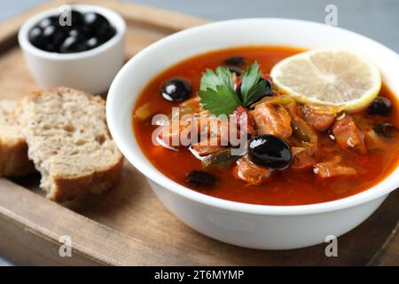 Soupe solyanka à la viande avec saucisses, olives et légumes dans un bol servi sur table, gros plan Banque D'Images