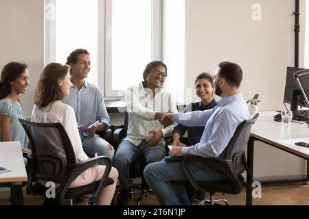 Des collègues d'affaires indiens et caucasiens confiants et joyeux serrant la main Banque D'Images