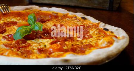 Une délicieuse pizza italienne traditionnelle sur une assiette sur la table en bois en bois sombre dans un restaurant italien Banque D'Images