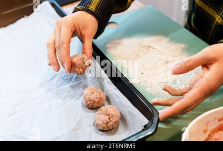 Cuisson des boulettes de viande faites à la main. Boulette de viande dans les mains féminines pendant la cuisson. Banque D'Images