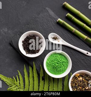 Herbe de thé sec de thé matcha vert avec fond de pierre noire de bâton de bambou Banque D'Images