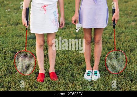 Fille de section basse debout herbe verte tenant le volant de badminton Banque D'Images