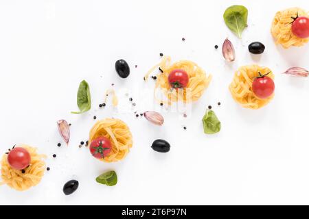 Pâtes crues fettuccine tomate cerise olive noir gousse d'ail feuilles de basilic isolé fond blanc Banque D'Images