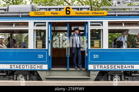 DAS Zürcher Tram - Elefant Ein Kontrolleur schaut ob alle Passagiere eingestiegen sind. DAS war in der Zeit des trams StStZ ce 4/4 321, welches 1930 an die Städtische Strasssenbahn Zürich abgeliefert wurde üblich. Besser bekannt ist das Tram unter dem Übername Elefant . 1966 wurde es ausrangiert und steht seit 1975 als Museumstram im Dienst der VBZ. Hier ist es auf der Linie 6 zwischen Zürich Hauptbahnhof und dem Zürich Zoo, anlässlich des Jubiläumsevents 175 Jahre Eisenbahn in der Schweiz im Einsatz. Zürich, Schweiz, 21.05.2022 *** le tramway de Zurich Elefant un inspecteur vérifie si tous Banque D'Images