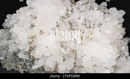 Druse de cristal de roche avec inclusions de pyrite. quartz blanc avec pyrite gros plan sur fond noir. Spécimen géologique de pierre semi-précieuse, sommet vi Banque D'Images